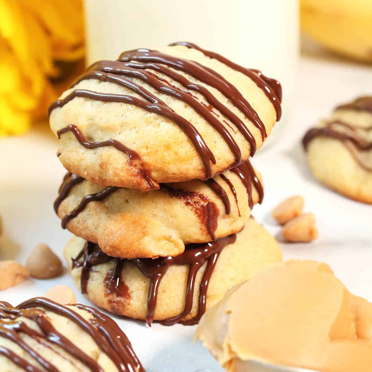 Closeup stacked cookies with spoon of peanut butter.
