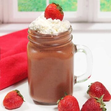 Smoothie in mason jar with whipped cream and strawberry.