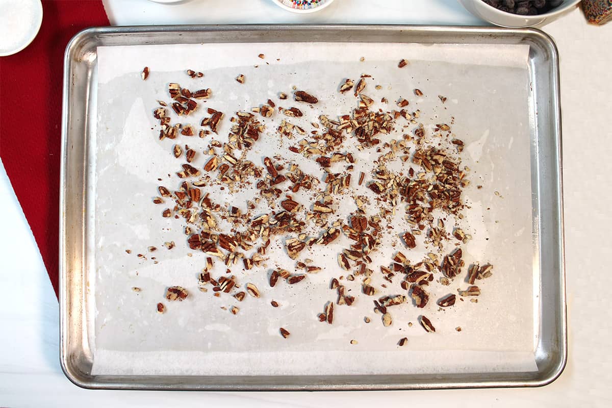 Chopped pecans on parchment lined cookie sheet.