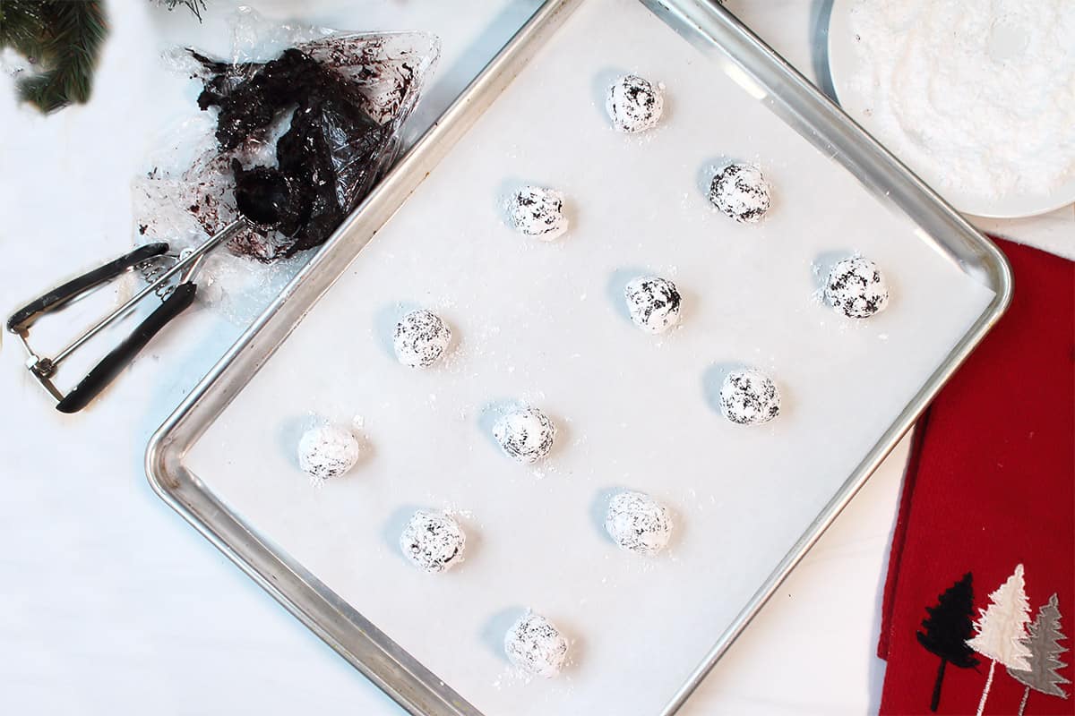 Cookie balls that have been rolled in sugar on cookie sheet.