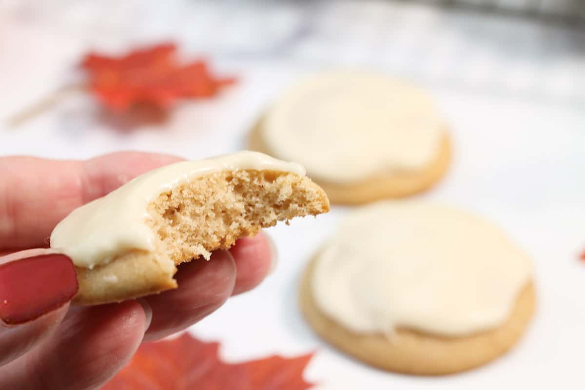 Holding a cookie with a bite our of it.