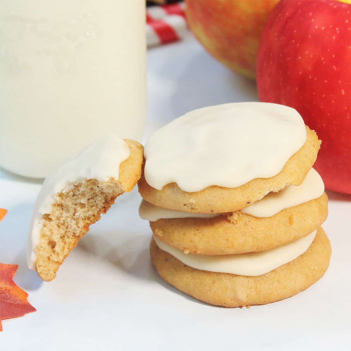 Closeup of stack of cookies with milk bottle and apples.