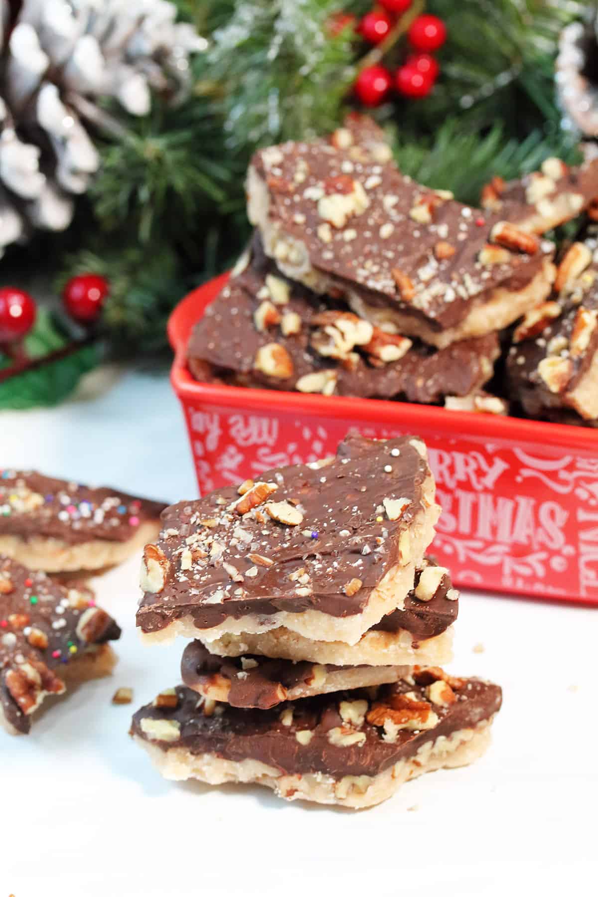 Stack of microwave toffee in front of red Christmas dish filled with same.