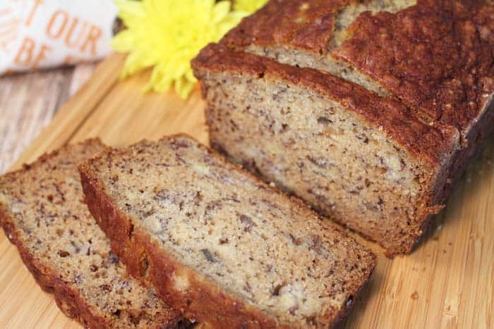 Closeup of sliced classic banana bread on wooden cutting board.