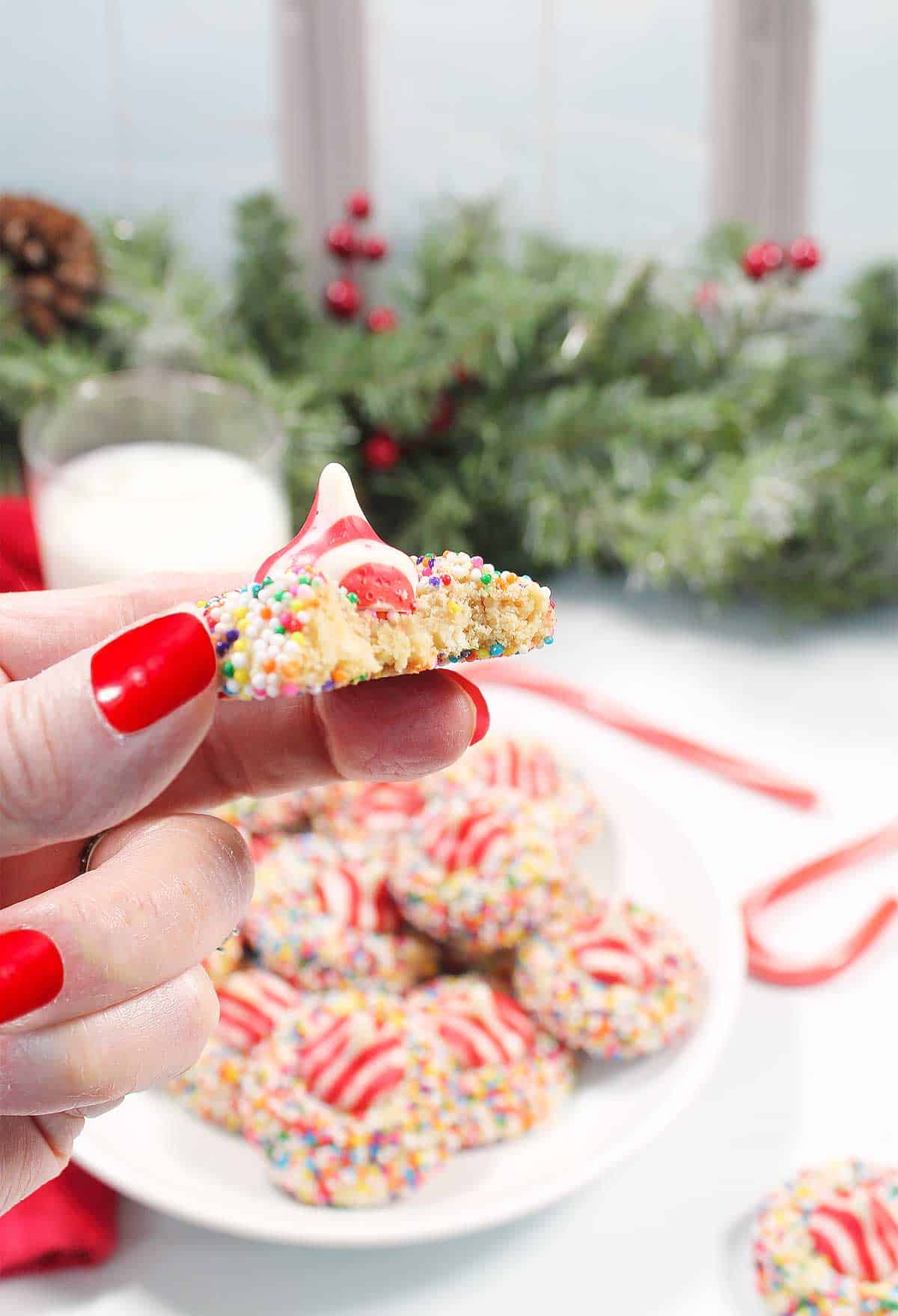 Holding a white chocolate peppermint kiss cookie with a bite out.