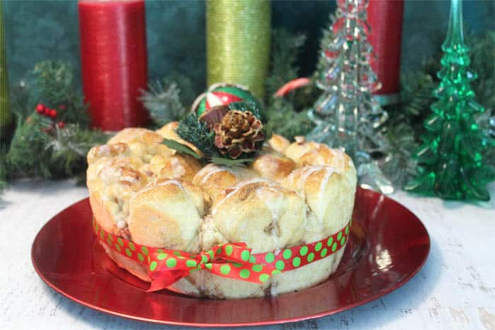 Monkey Bread on red charger with red & green ribbon around it and pinecone topper.