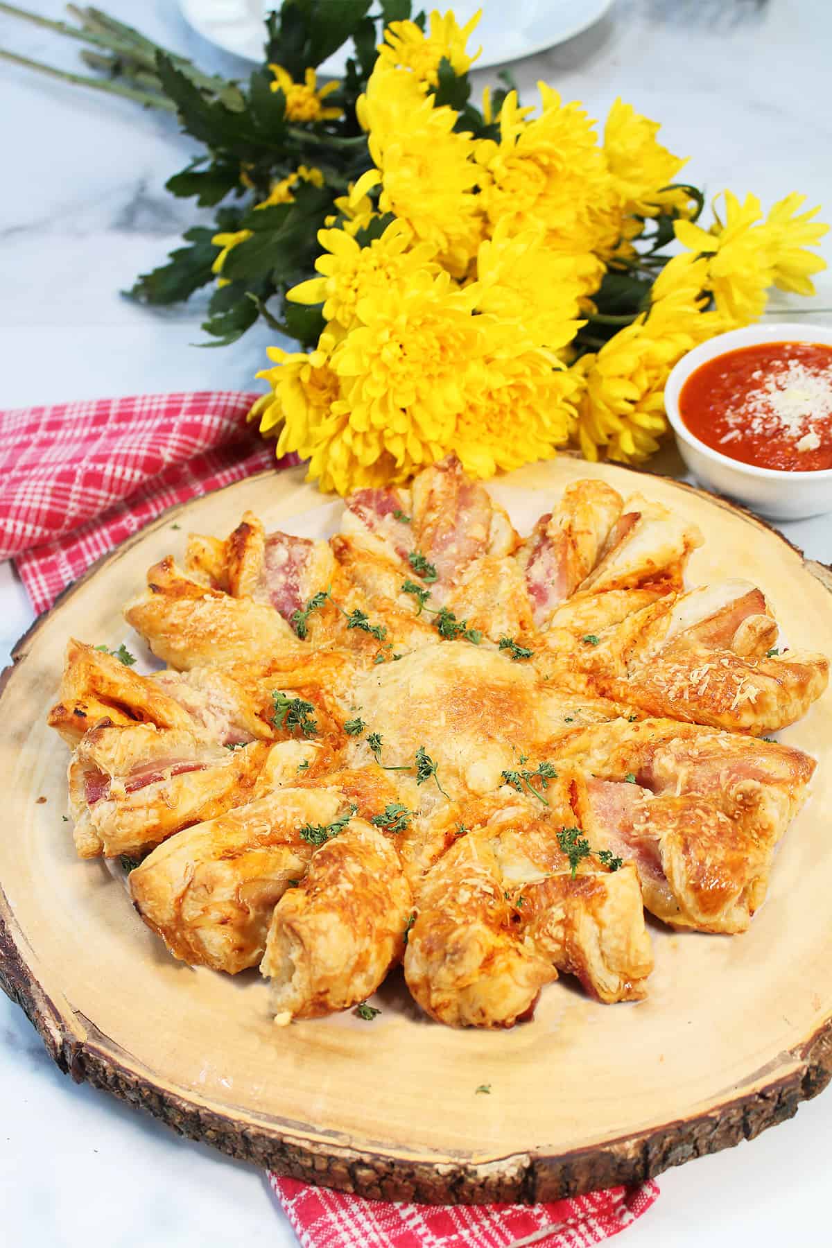 Puff Pastry Pizza Twists on wooden board with yellow flowers.
