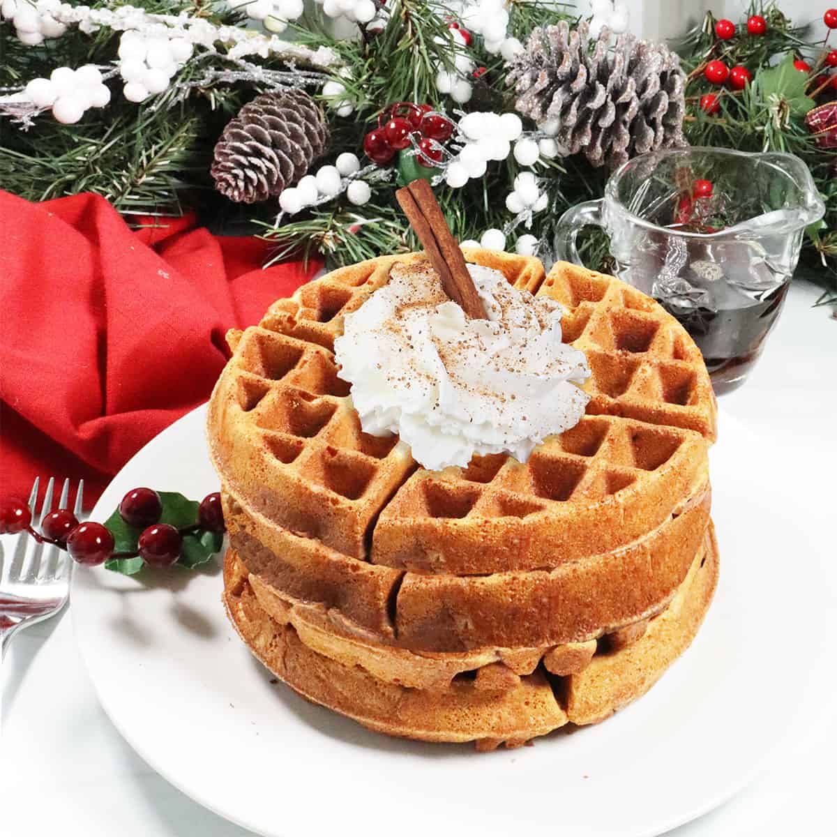 Eggnog Waffles stacked on a plate with whipped cream.