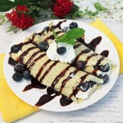 Plated sweet crepes with chocolate drizzle and whipped cream on top.