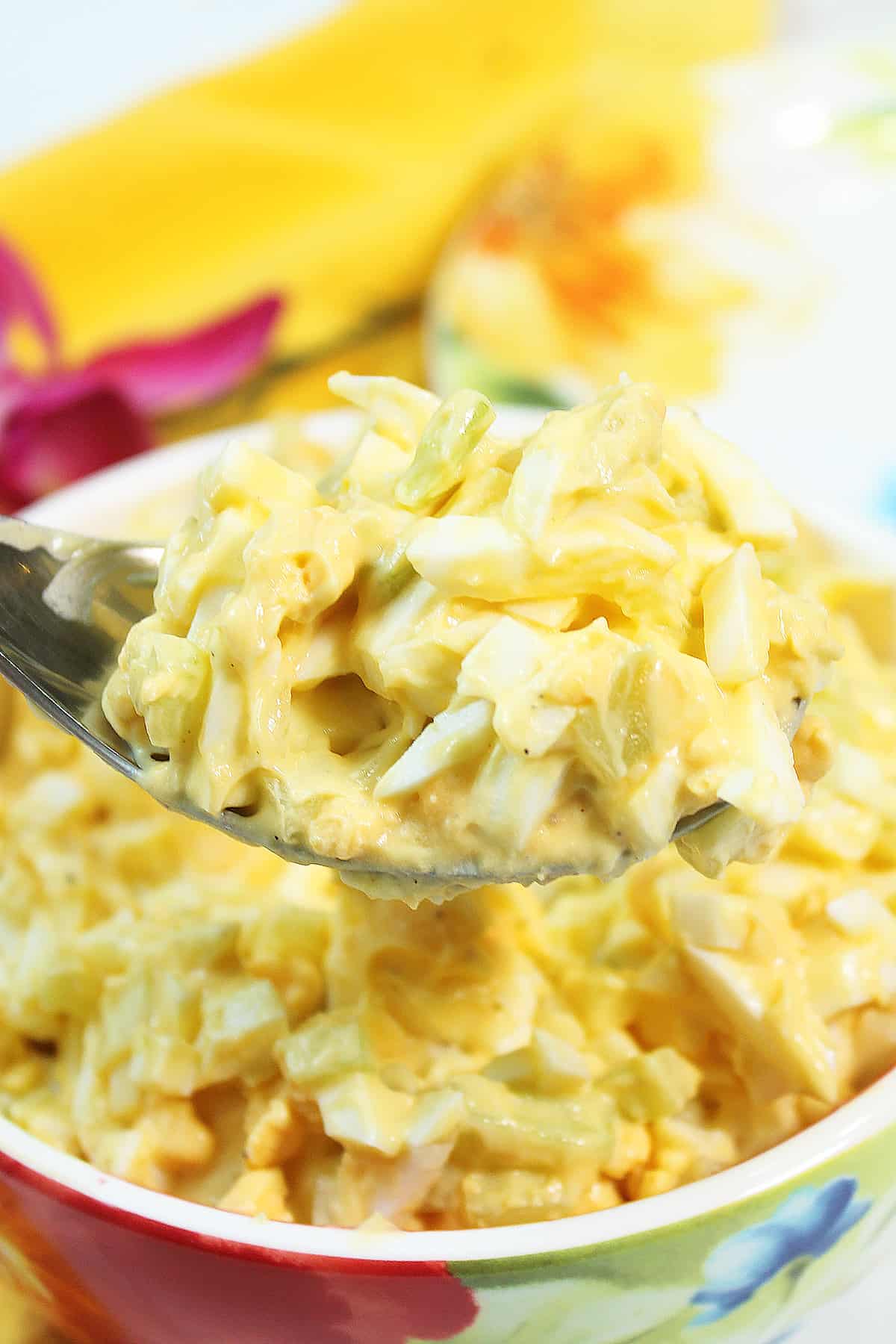 Spoonful of easy egg salad over bowl.