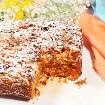 Cake with slice out and flowers in back.