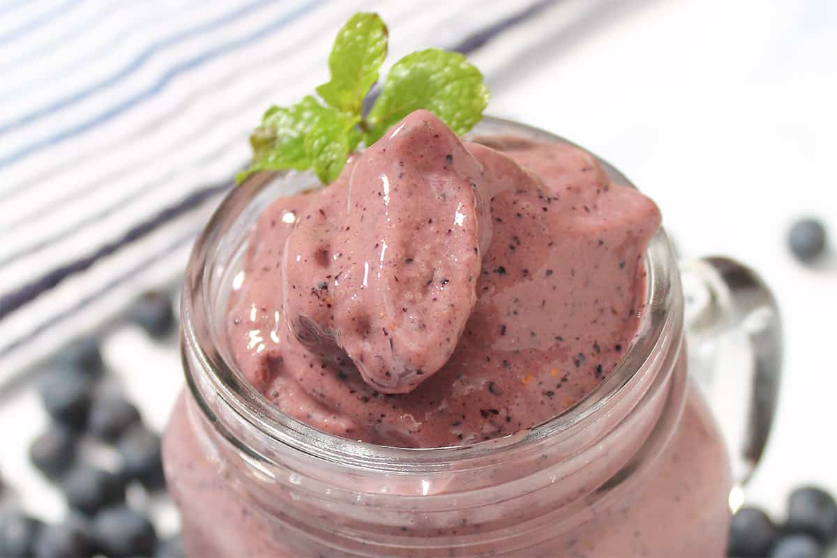 Closeup of top of smoothie in mason jar with mint sprig.