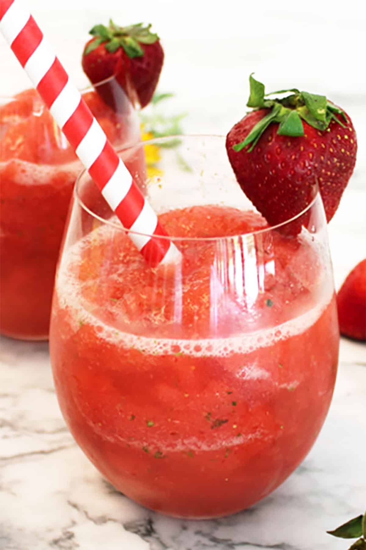 Closeup of strawberry mule with strawberry garnish and red and white straw.