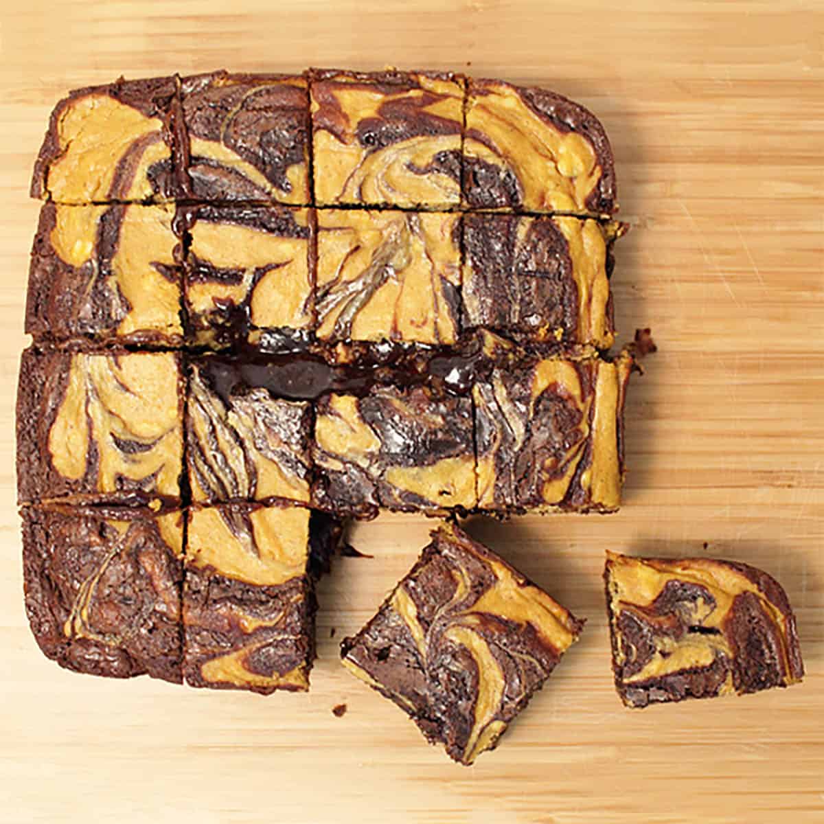 Overhead of brownies cut into bars on wooden cutting board.