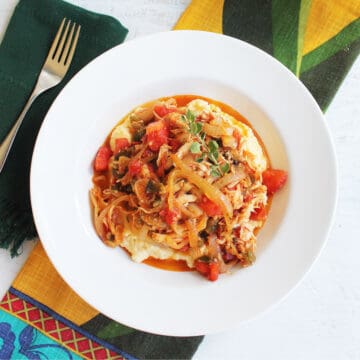 Overhead of chicken stew in white bowl on colorful linen.