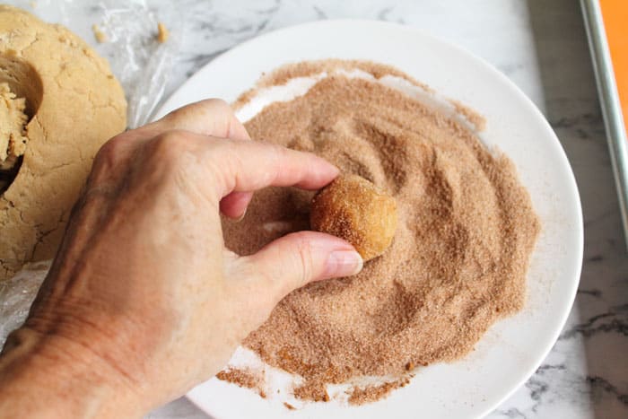 Peanut Butter Snickerdoodles rolling in cinnamon sugar | 2 Cookin Mamas