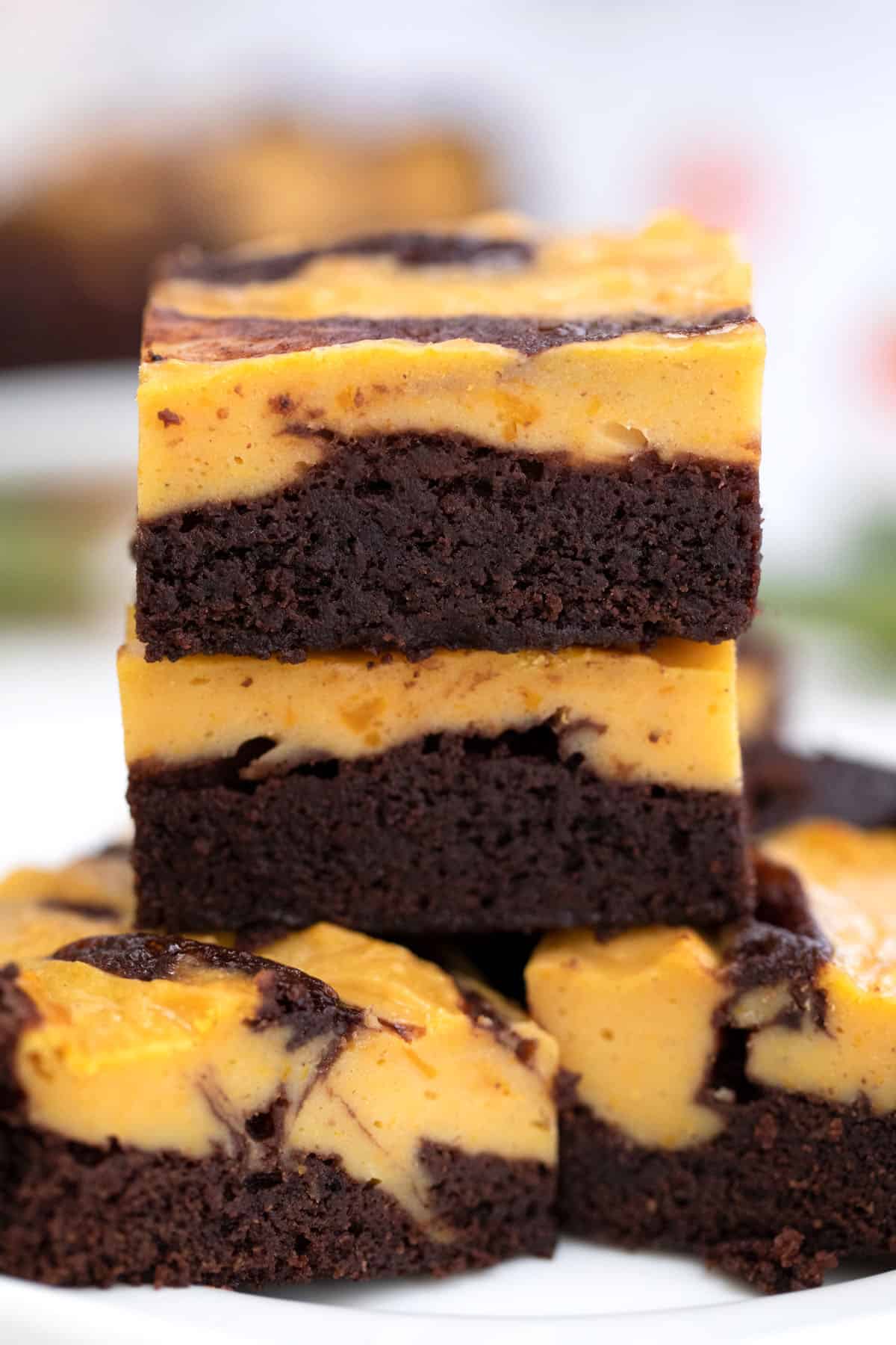 Stacked brownies showing layer of brownies and layer of pumpkin cheesecake.