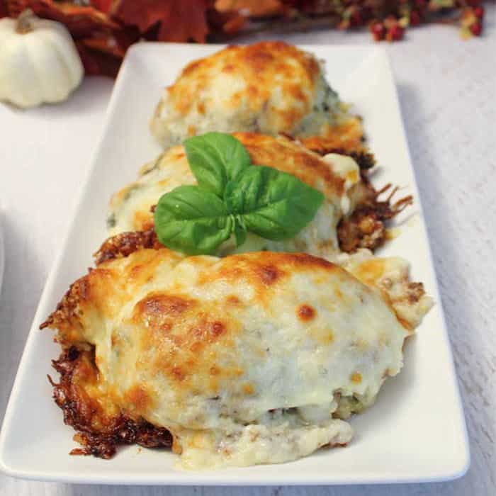 Baked roll ups with browned cheese on top and plated on white platter.