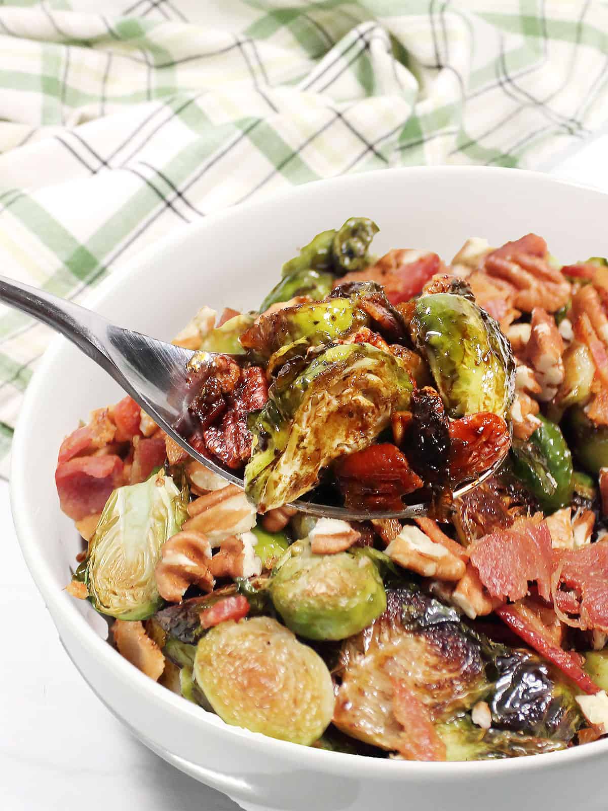 Spoonful of roasted brussels sprouts over serving bowl.