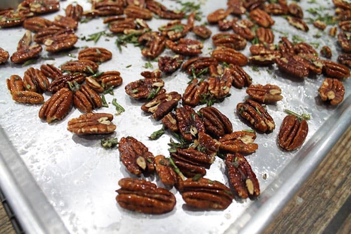 Closeup of roasted rosemary pecans on cookie sheet.