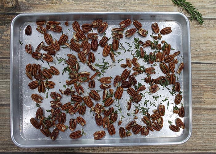 Pecans and rosemary are sprinkled on a large cookie sheet.