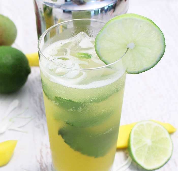 Closeup of Sparkling Mango Mojito withe lime garnish and mint leaves.