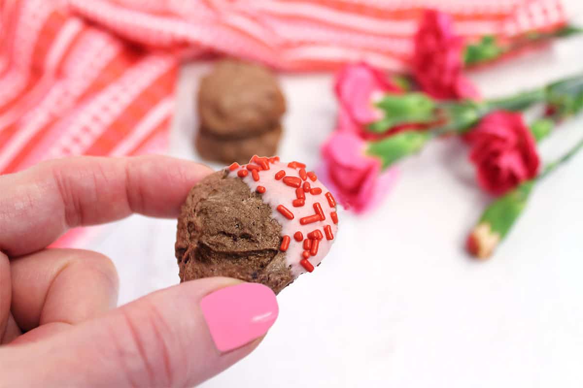 Holding meringue cookie with sprinkles.