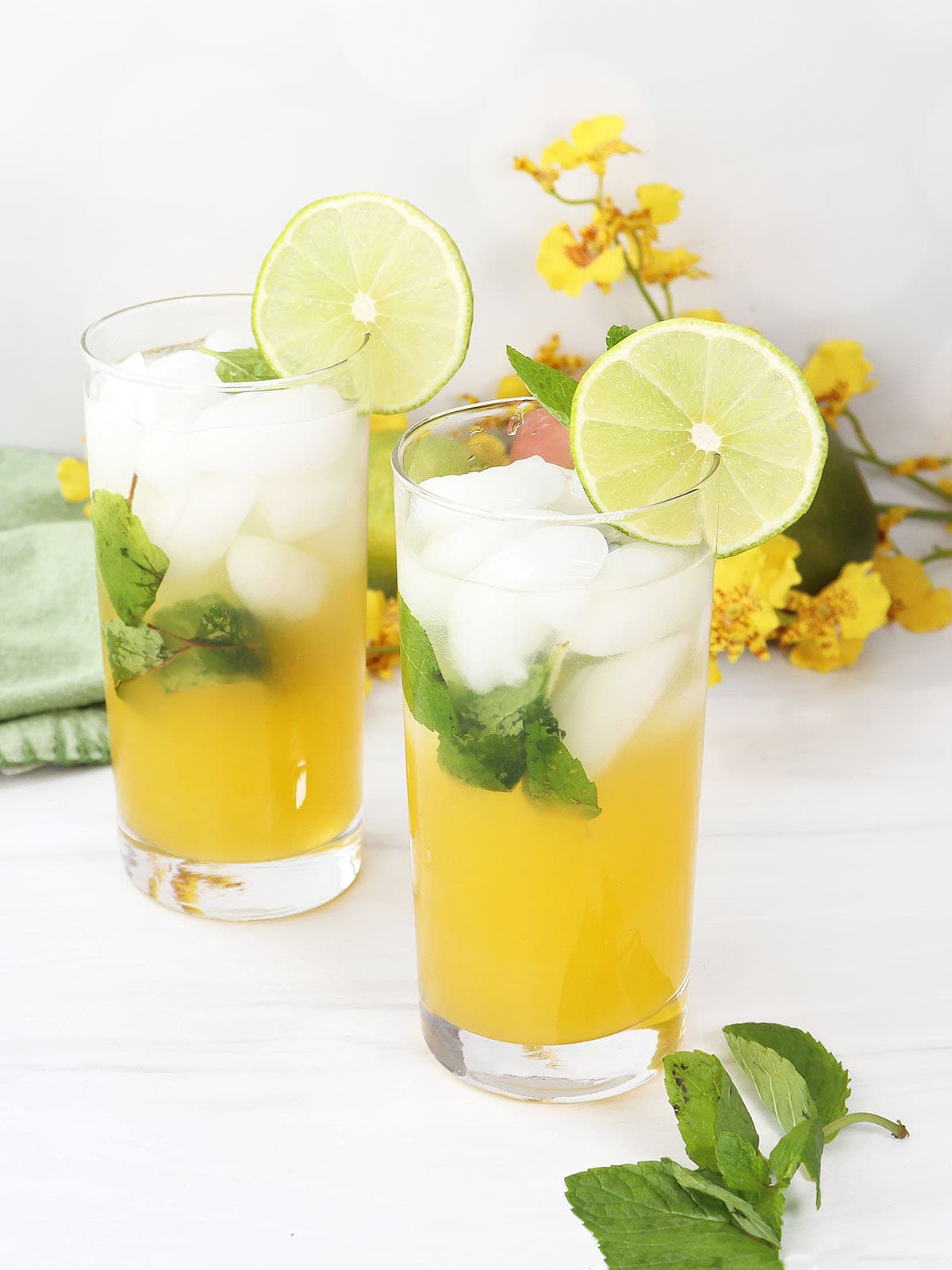 Two Mango Mojitos with tequila and a lime garnish.