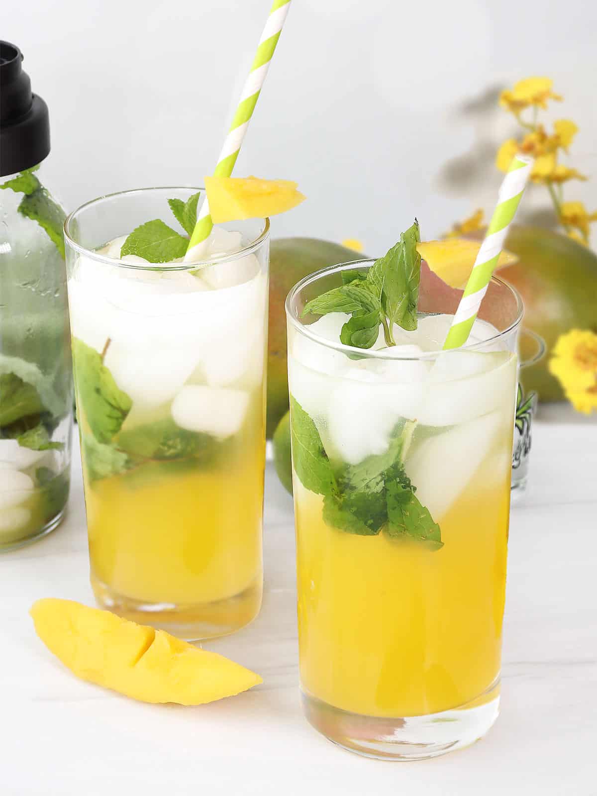 Two mango mojitos with mint and straws.