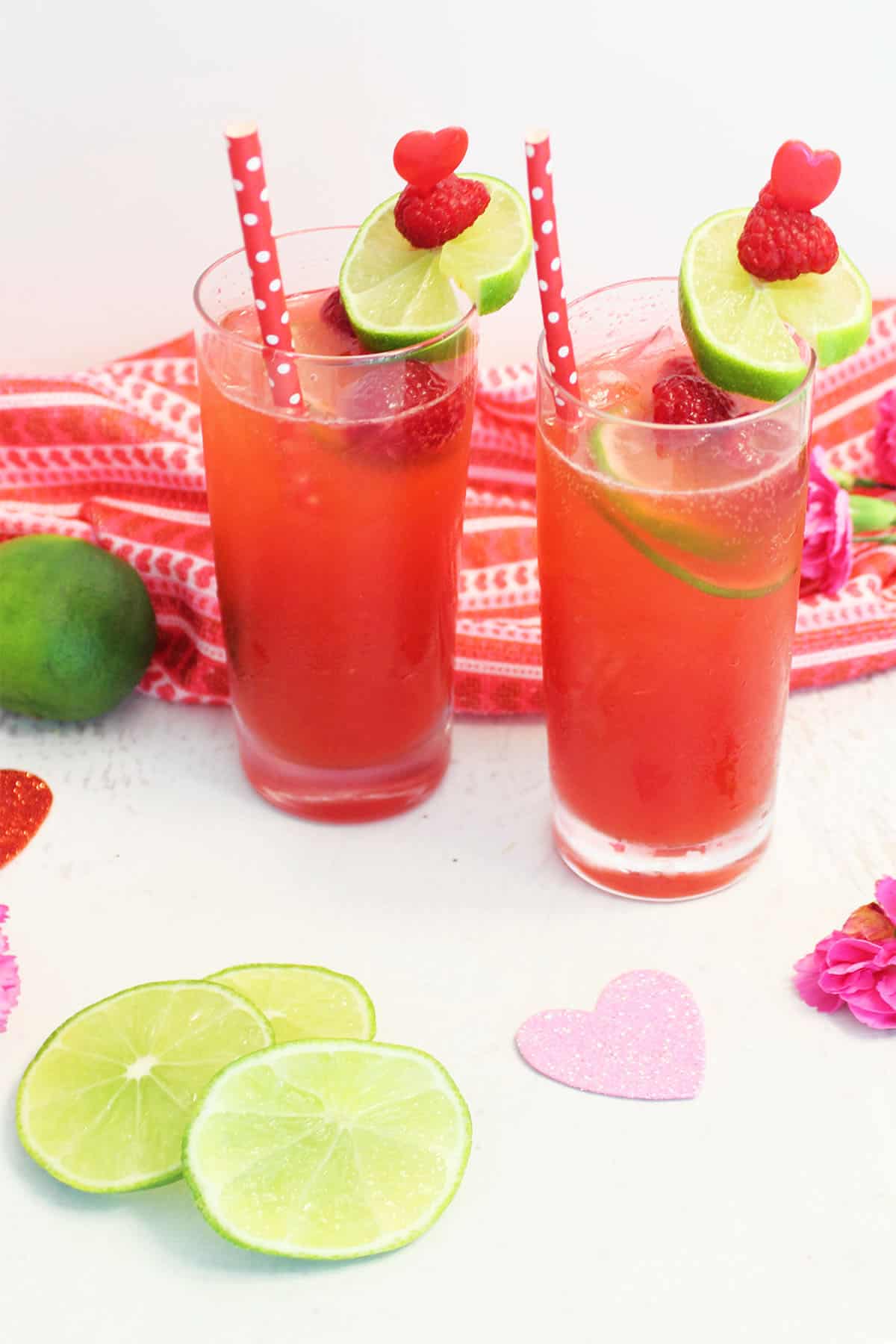 Two drinks with straws with Valentines Day towel flowers and lime slices.