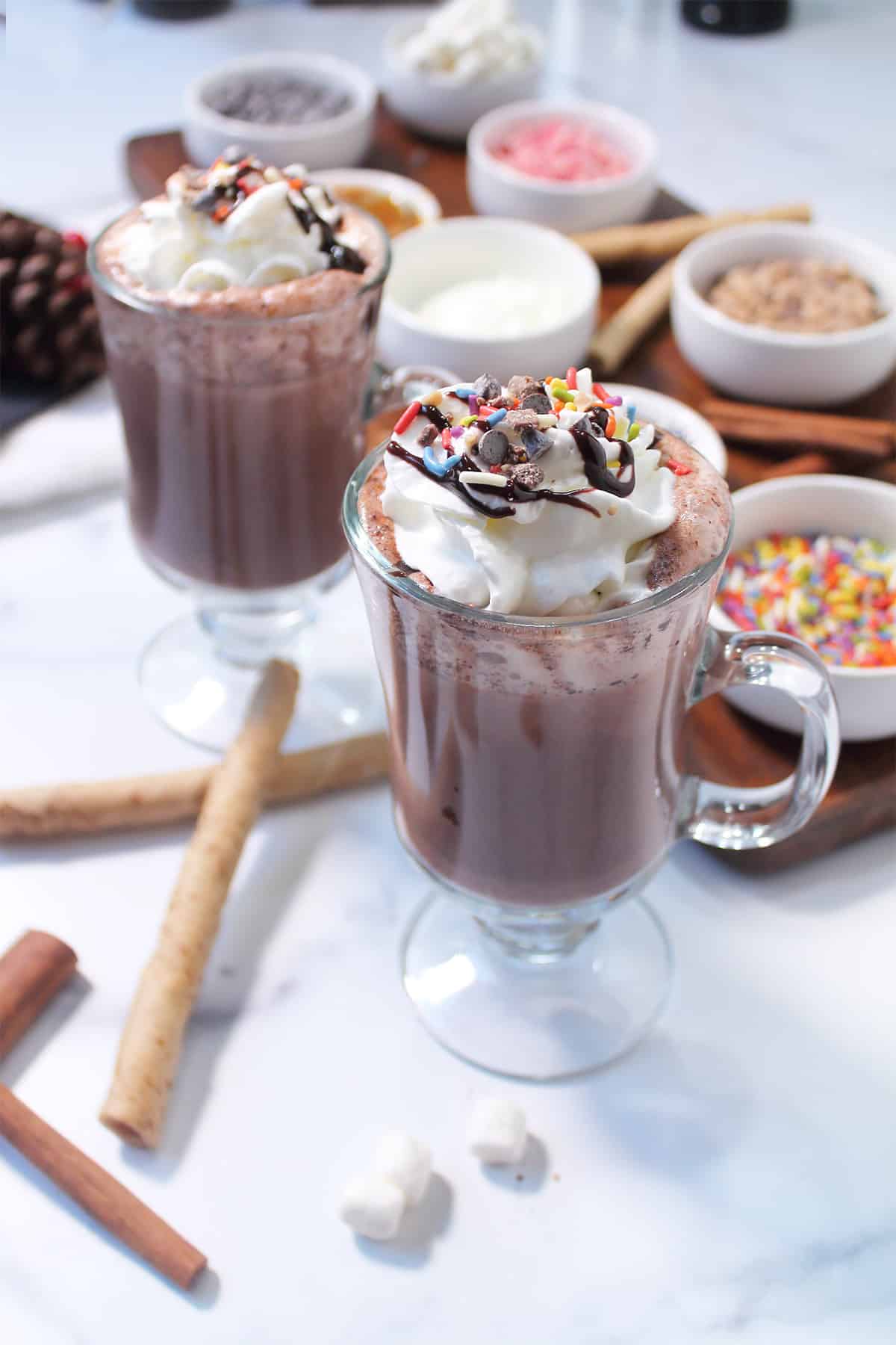 Two mugs of Kahlua Hot Chocolate beside hot chocolate bar.