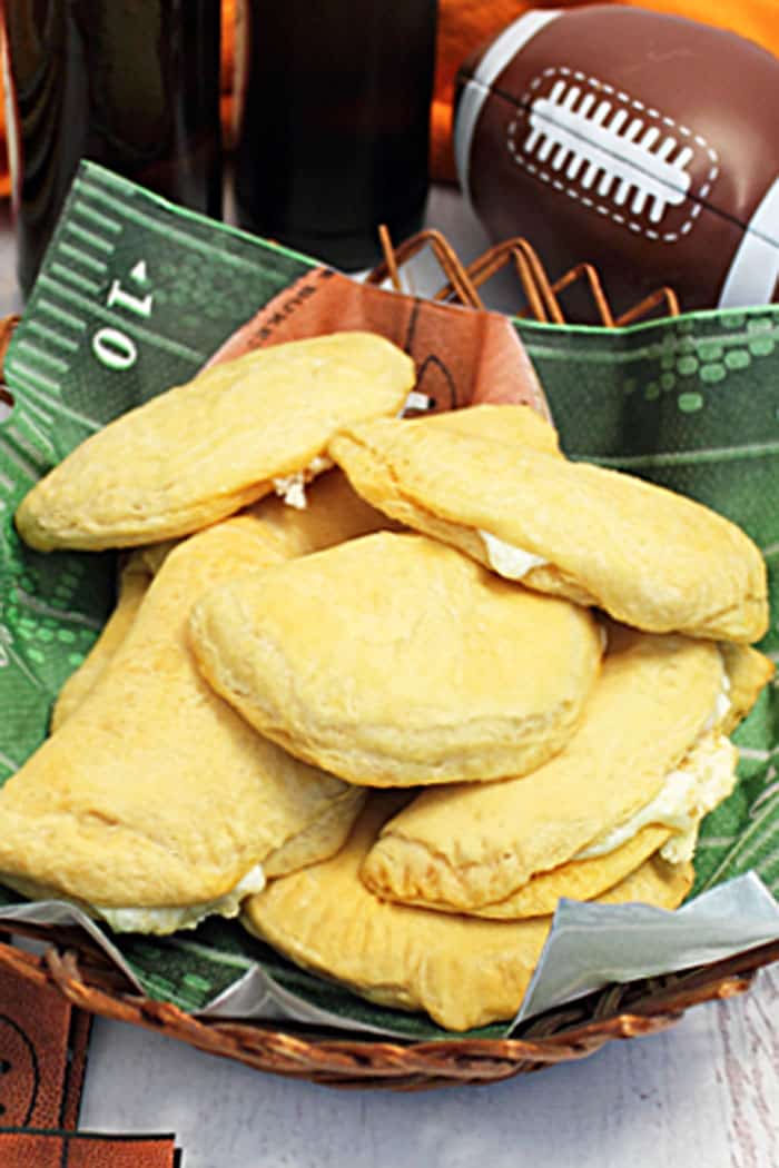 Pepperoni pizza pockets in basket with football in the background.