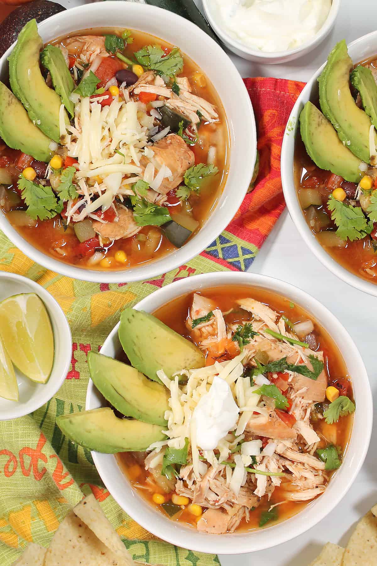 Overhead of three bowls of tortilla soup with garnish.