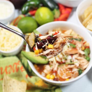 Spoonful of tortilla soup above bowl.