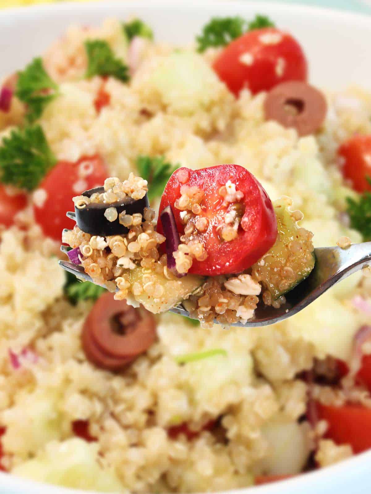 Bite of Mediterranean salad with quinoa on fork.