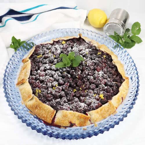 Easy Blueberry Galette on serving plate with powdered sugar mint garnish.