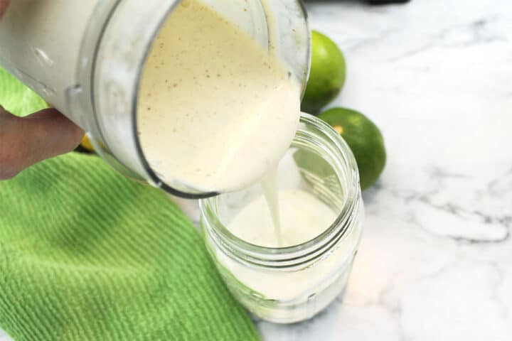 Pouring blended smoothie into mason jar.