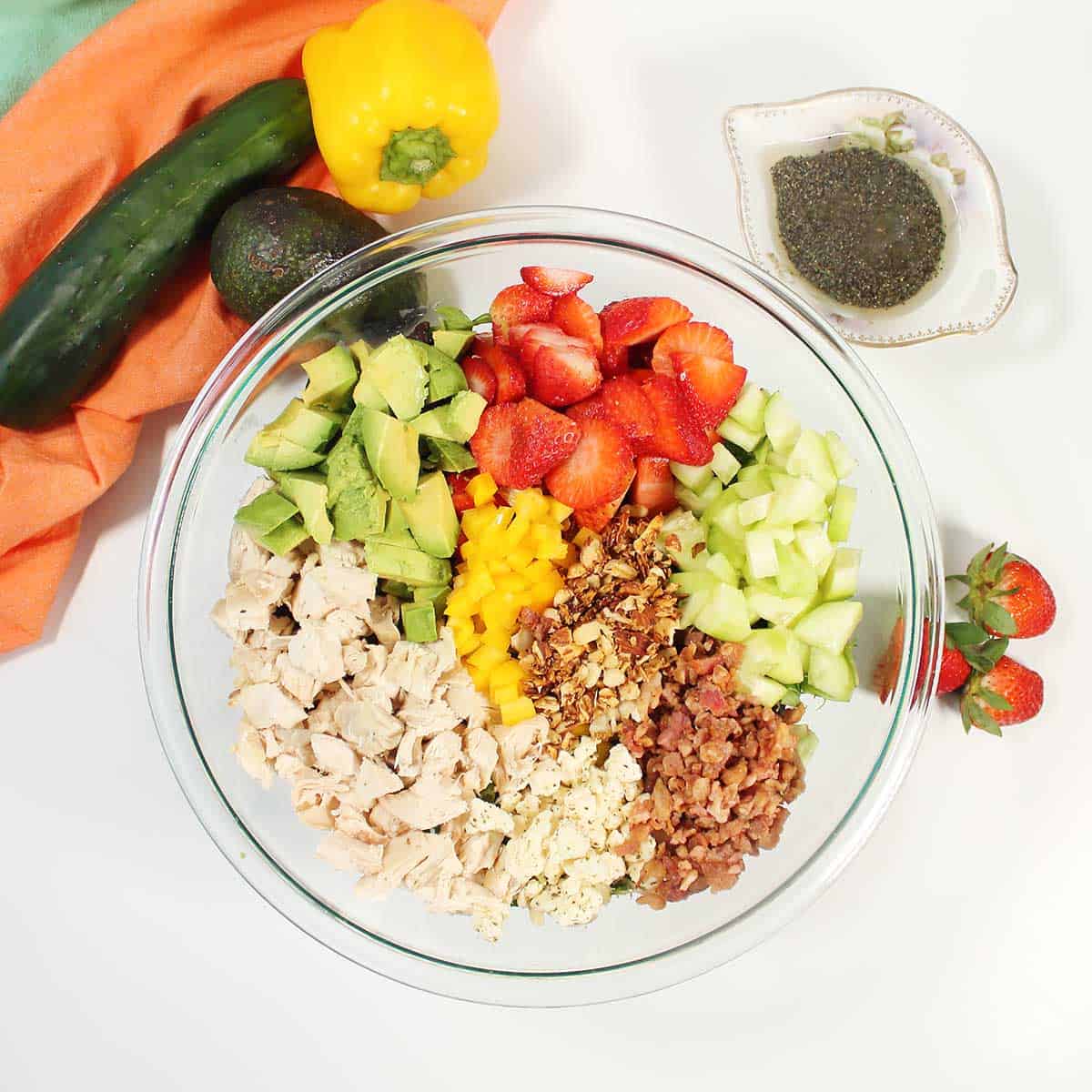 All ingredients for avocado strawberry salad in a large bowl.