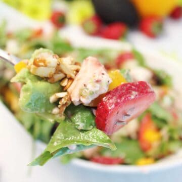 Forkful of salad over salad bowl.