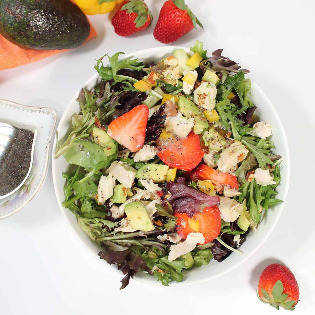 Overhead of avocado strawberry salad in white bowl.