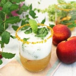 Bubbling Peach Mint Julep with gold sugar rim on peach napkin.