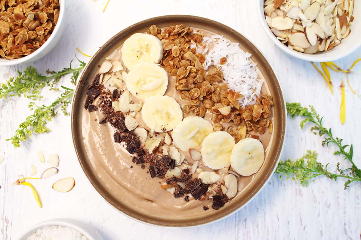 Chocolate smoothie in bowl finished with toppings.