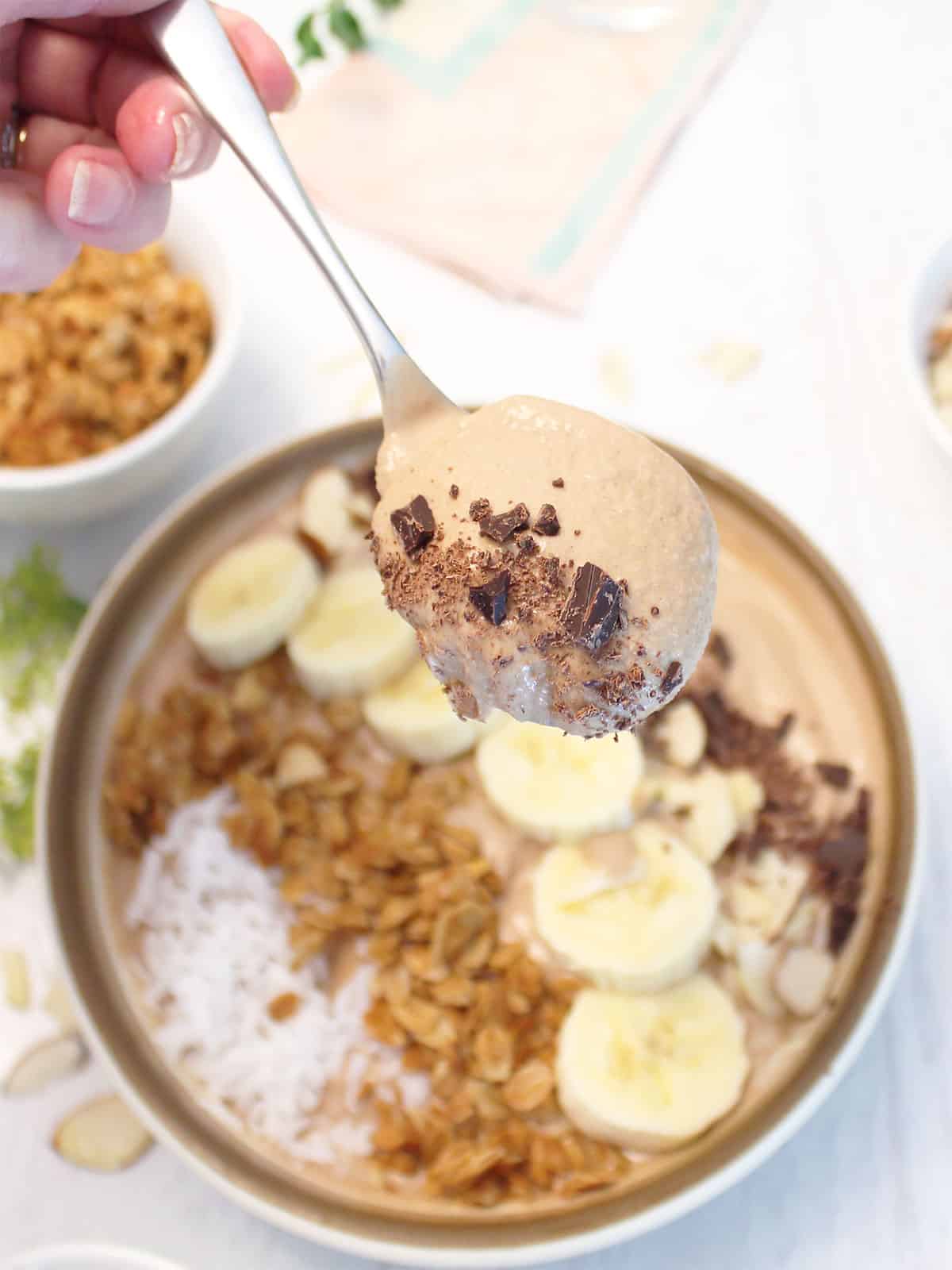 Spoonful of chocolate smoothie over bowl.