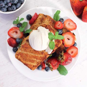 Overhead of topped grilled cake with ice cream, berries and mint.