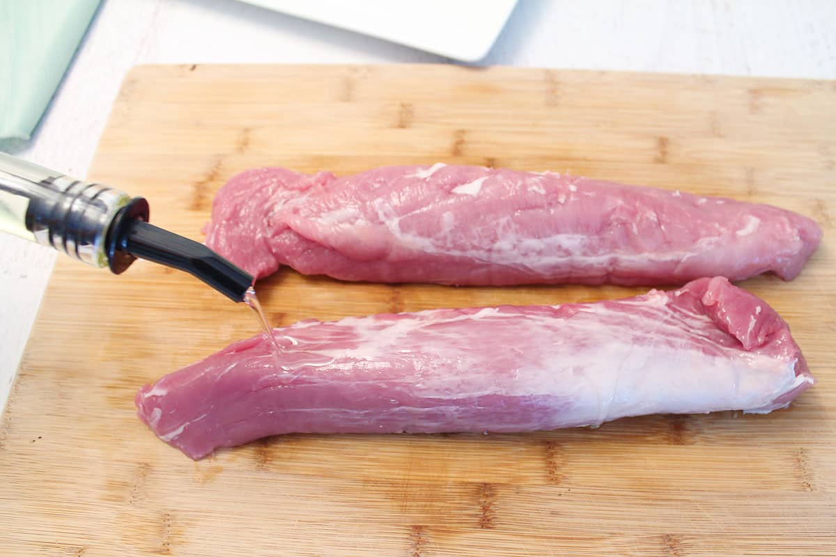 Covering pork tenderloin with olive oil.