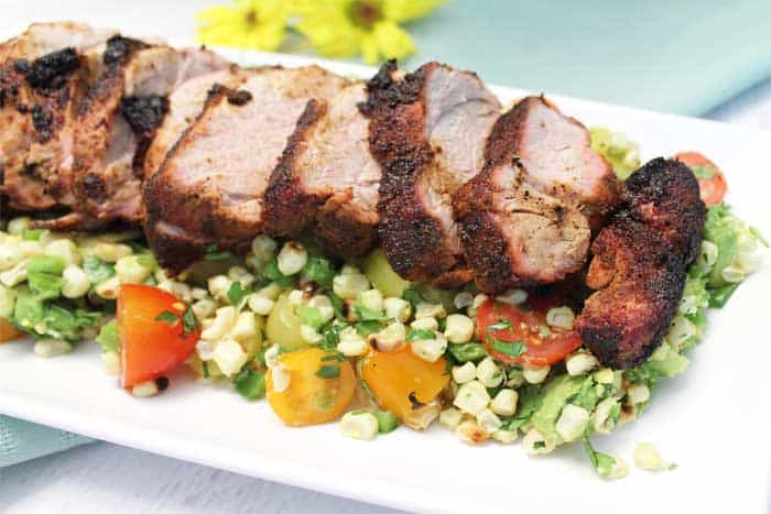 Sliced grilled pork tenderloin on white plate with Tomato Corn Salsa.