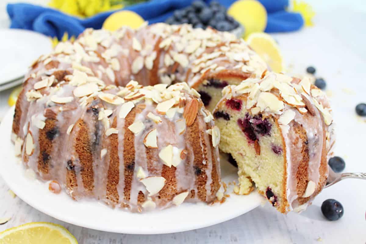 Slicing the bundt cake to show the inside of the cake studded with blueberries.