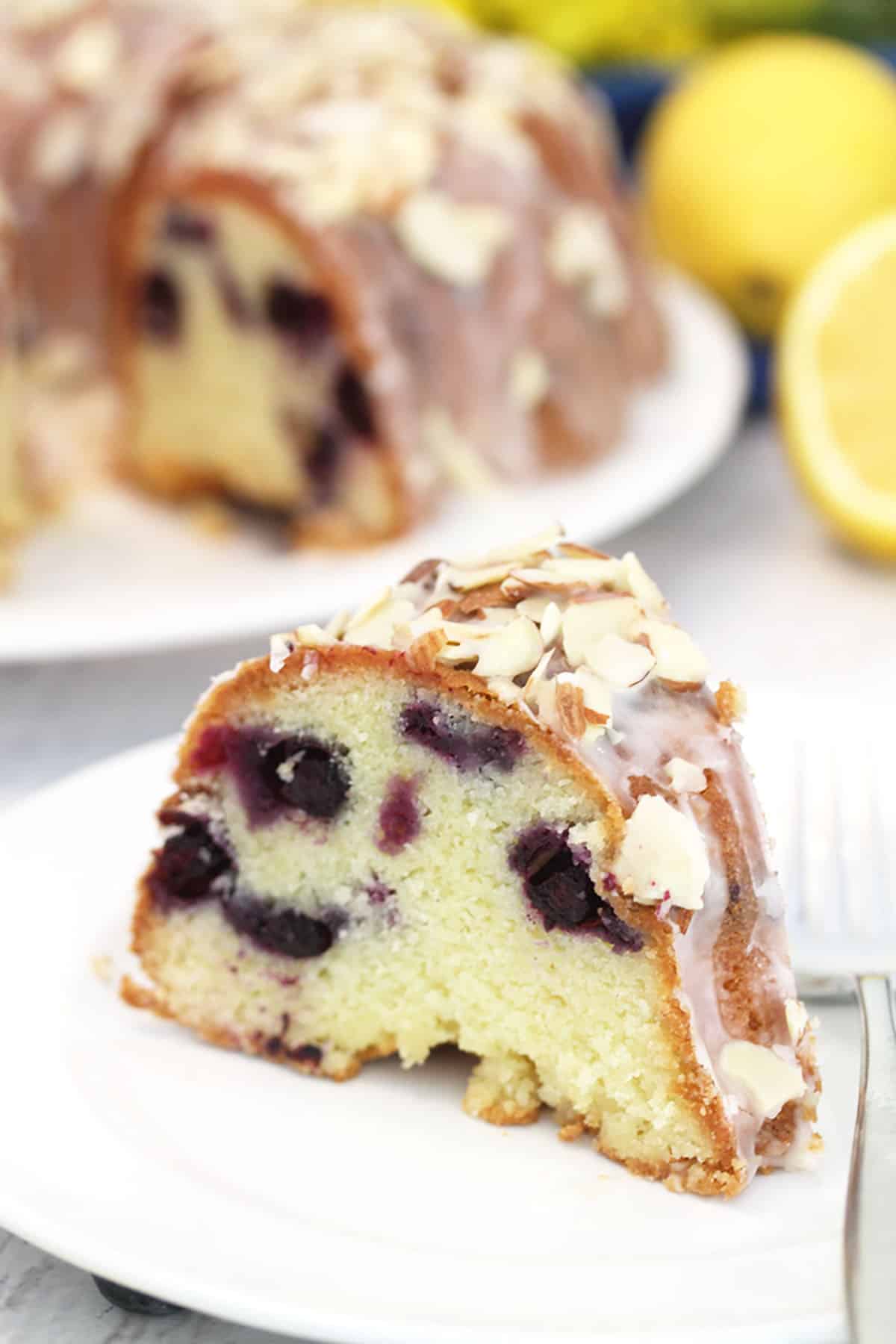 Showing cake slice on white plate in front of whole cake.