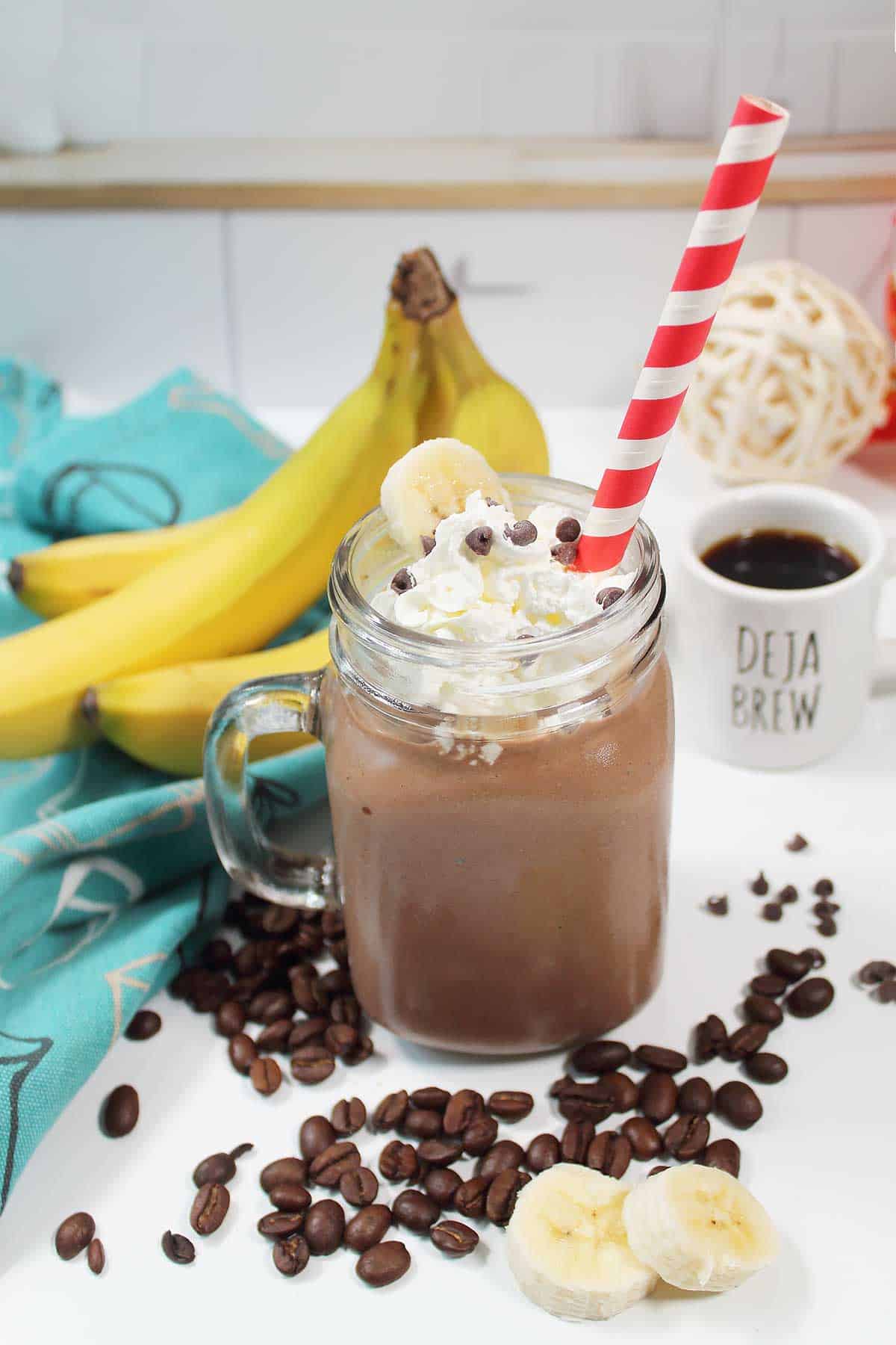 Coffee smoothie with whipped cream topping by bananas.