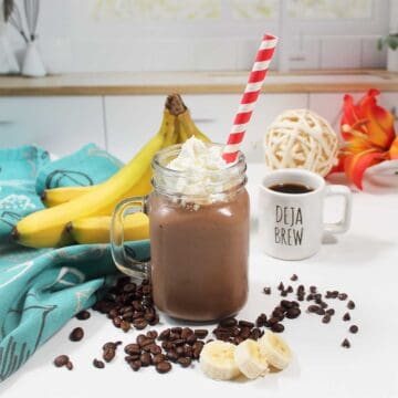 Coffee smoothie with a red striped straw on kitchen counter.